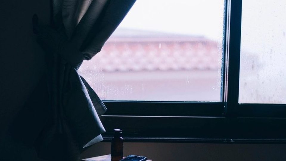 A curtain hanging at a window, backlit by pale morning light.