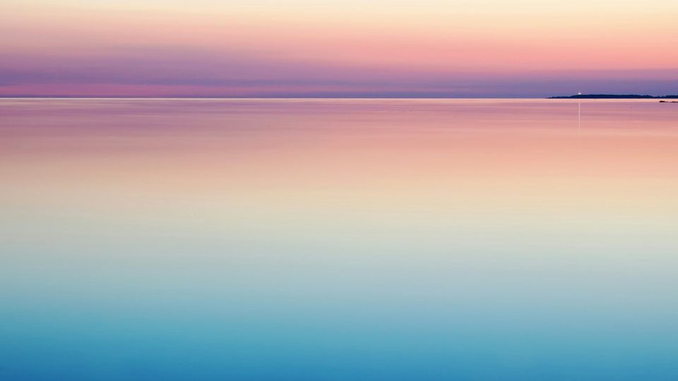 Flat sea under a sky banded pink and blue.