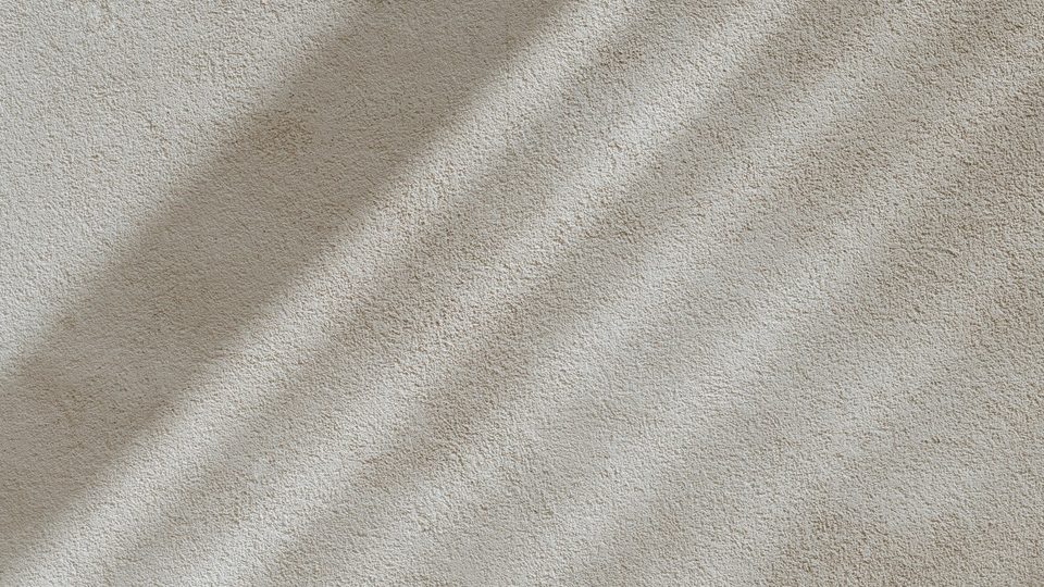 Light and shadow falling across a textured surface in warm neutral tones.